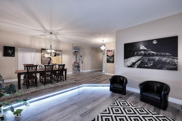 sitting room featuring arched walkways, wood finished floors, and baseboards