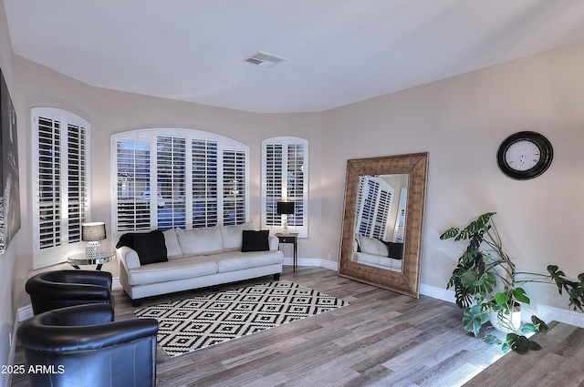 living room with visible vents, baseboards, and wood finished floors