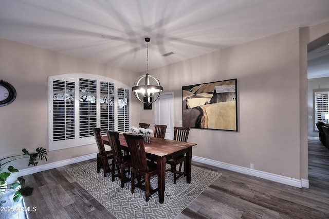 dining space featuring baseboards, visible vents, dark wood finished floors, and a notable chandelier