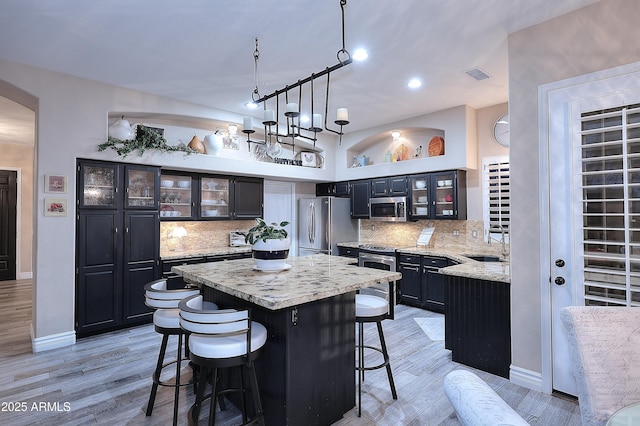 kitchen featuring glass insert cabinets, visible vents, a kitchen island, and appliances with stainless steel finishes