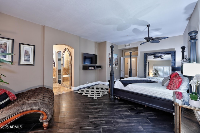 bedroom with dark wood-style floors, baseboards, visible vents, and ensuite bath