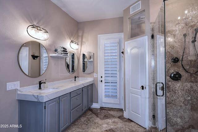 bathroom featuring visible vents, a sink, a shower stall, and double vanity