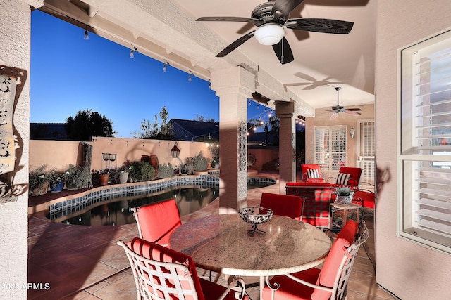 patio terrace at dusk featuring outdoor dining area, a fenced backyard, a ceiling fan, and a fenced in pool