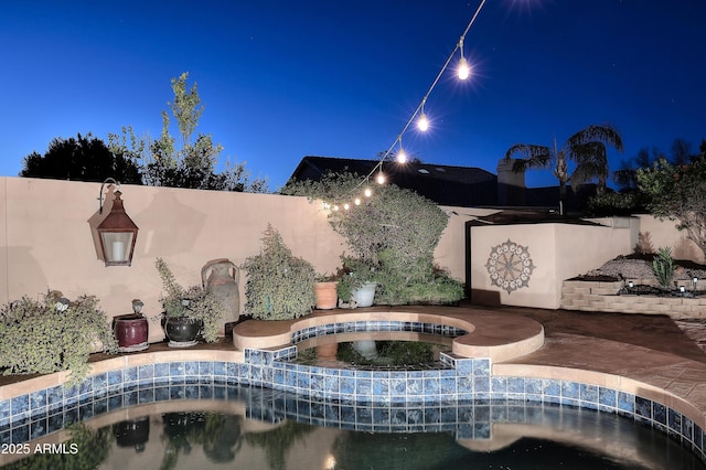 patio at night with an in ground hot tub