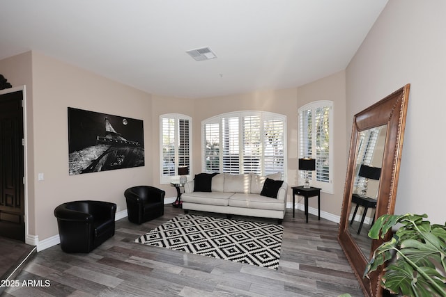 living area with wood finished floors, visible vents, and baseboards