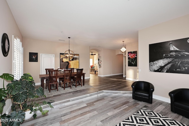 living room with arched walkways, a notable chandelier, baseboards, and wood finished floors