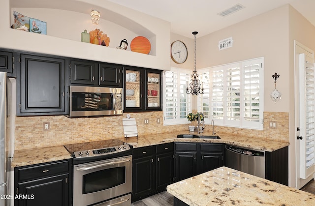 kitchen with hanging light fixtures, appliances with stainless steel finishes, a sink, and dark cabinetry