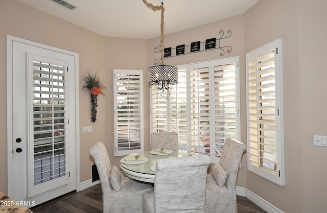 dining room with a chandelier, dark wood-type flooring, visible vents, and baseboards