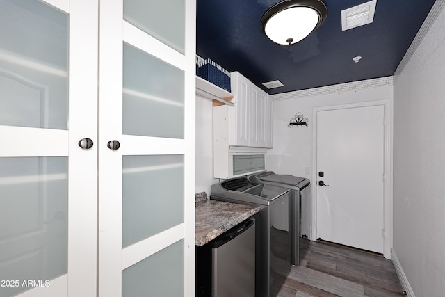 clothes washing area with cabinet space, visible vents, dark wood finished floors, and washing machine and clothes dryer