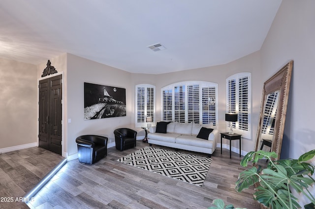 living area with visible vents, baseboards, and wood finished floors