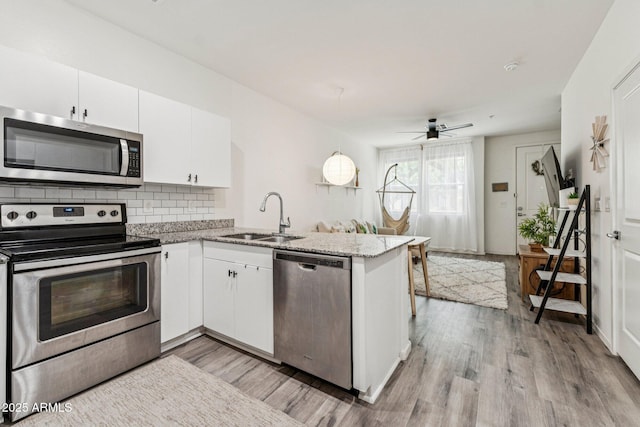 2313 E Hidalgo Ave, Phoenix, AZ 85040 - kitchen with appliances with stainless steel finishes, a peninsula, white cabinetry, and light wood-style floors