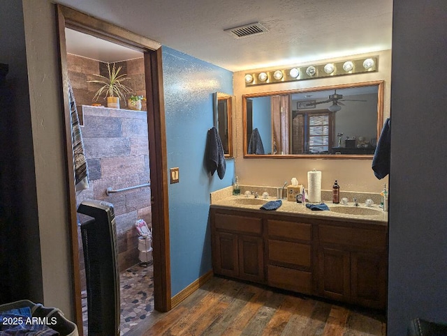 full bathroom with double vanity, visible vents, a sink, and wood finished floors