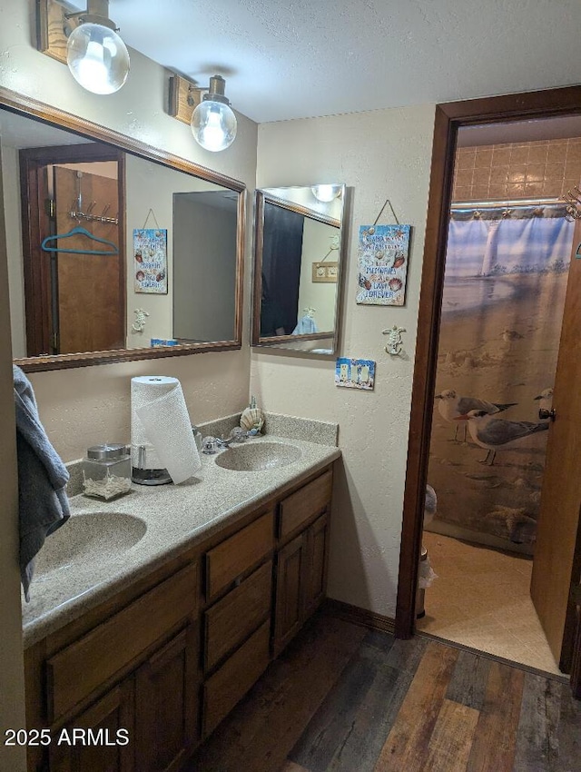 bathroom with double vanity, wood finished floors, curtained shower, a textured ceiling, and a sink