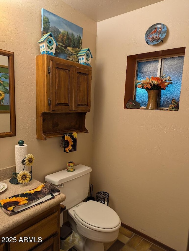 bathroom with baseboards, vanity, and toilet