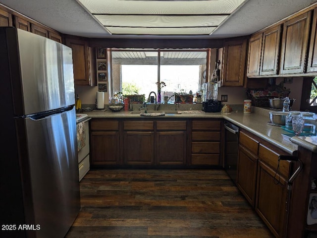 kitchen with dishwashing machine, stove, a sink, freestanding refrigerator, and dark wood-style floors