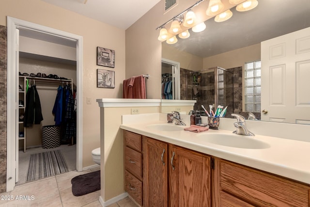 bathroom with vanity, toilet, tile patterned flooring, and a tile shower