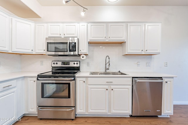 kitchen featuring decorative backsplash, appliances with stainless steel finishes, sink, white cabinets, and light hardwood / wood-style floors