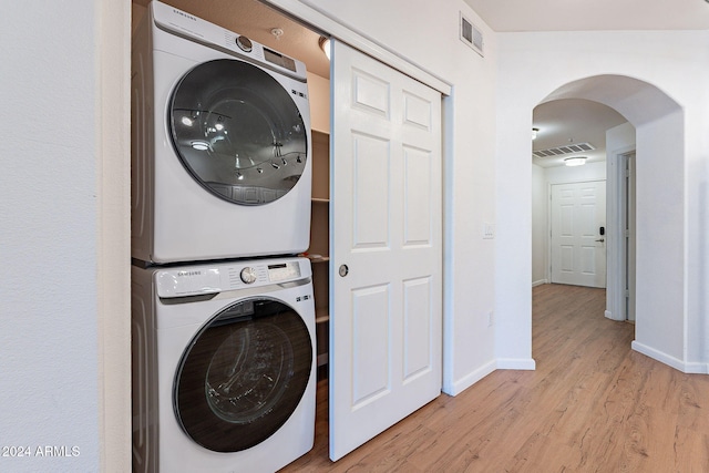 laundry area with light wood-type flooring and stacked washing maching and dryer