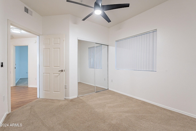 unfurnished bedroom with light carpet, a closet, and ceiling fan