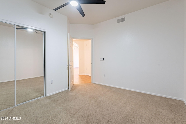 unfurnished bedroom featuring ceiling fan, a closet, and light colored carpet