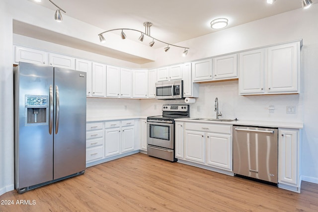 kitchen with appliances with stainless steel finishes, light wood-type flooring, white cabinetry, and sink