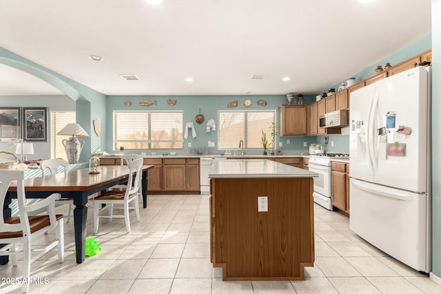 kitchen with a kitchen island, white appliances, sink, and light tile patterned floors