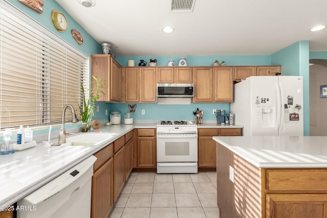 kitchen featuring white appliances, sink, and light tile patterned floors