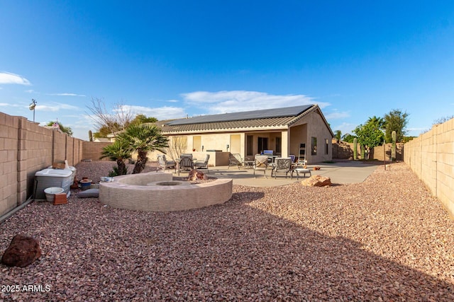 rear view of property with solar panels and a patio