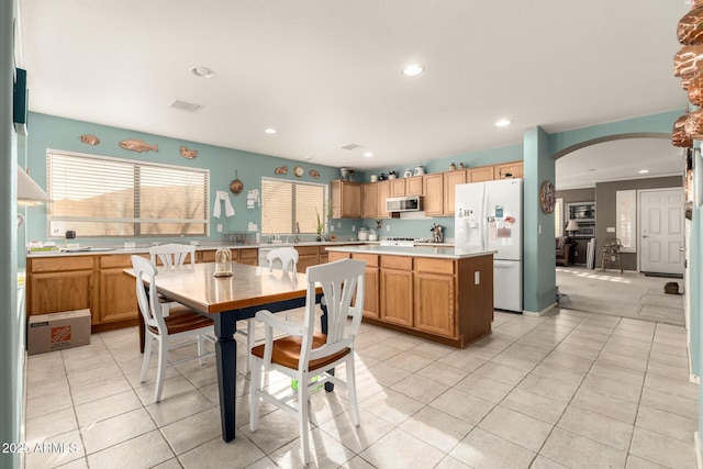 kitchen with white fridge with ice dispenser, a center island, and light tile patterned floors