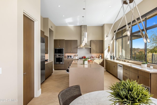 8145 E Tecolote Cir, Scottsdale, AZ 85266 - kitchen with a towering ceiling, wall chimney exhaust hood, modern cabinets, hanging light fixtures, and light countertops