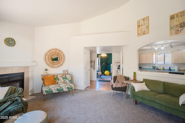 living area featuring light carpet, a tile fireplace, and high vaulted ceiling