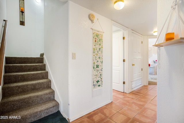 stairway featuring a textured ceiling, baseboards, and tile patterned floors