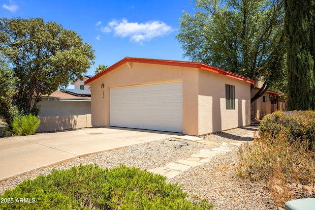 view of side of home featuring a garage, stucco siding, and driveway