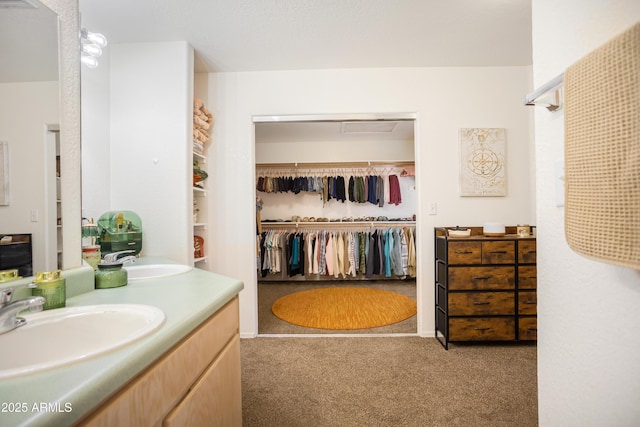 full bath with double vanity, a walk in closet, and a sink