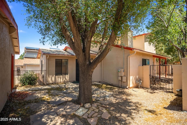 back of house with a gate, stucco siding, fence, and a patio