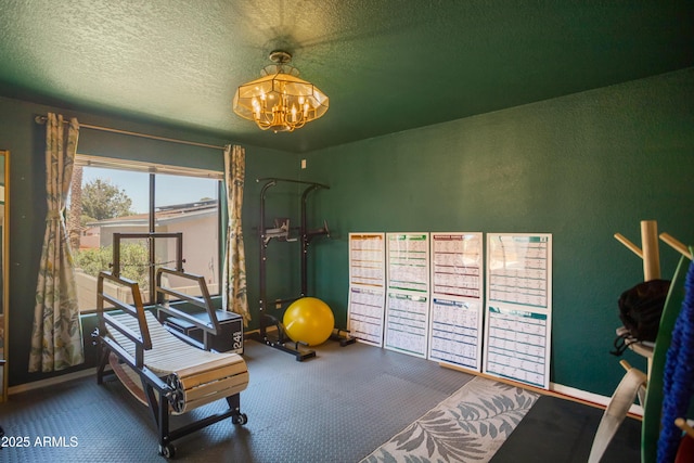 workout area featuring a textured ceiling, a chandelier, and a textured wall