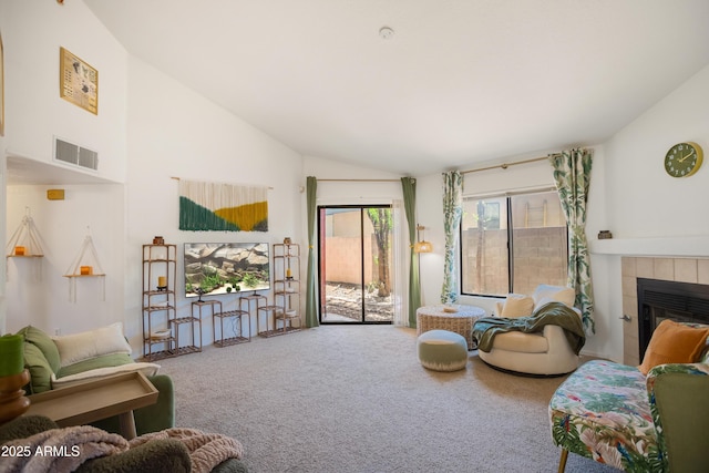 carpeted living area featuring a tile fireplace, visible vents, and high vaulted ceiling