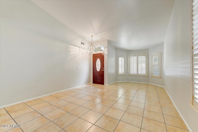 tiled entrance foyer featuring lofted ceiling, a chandelier, and a textured ceiling