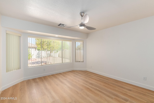 spare room with ceiling fan, light hardwood / wood-style flooring, and a textured ceiling