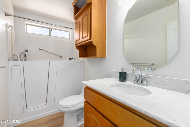 bathroom featuring a washtub, toilet, wood-type flooring, and vanity