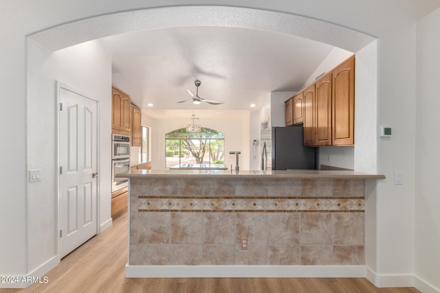 kitchen with ceiling fan, sink, stainless steel appliances, kitchen peninsula, and light hardwood / wood-style floors