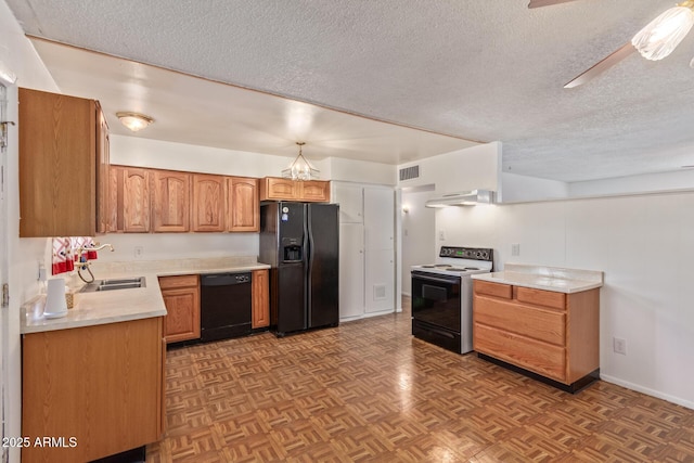 kitchen featuring ventilation hood, light parquet floors, a textured ceiling, black appliances, and ceiling fan with notable chandelier