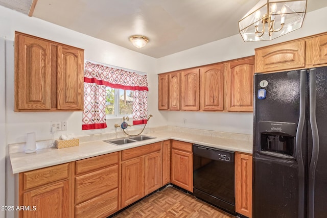 kitchen featuring sink, an inviting chandelier, light parquet floors, pendant lighting, and black appliances