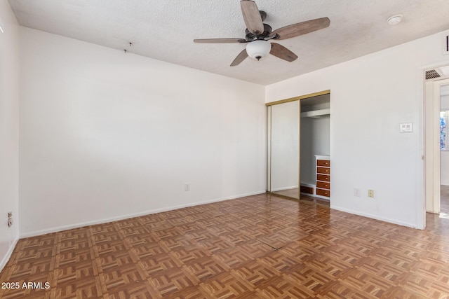 unfurnished bedroom with a textured ceiling, dark parquet floors, and ceiling fan