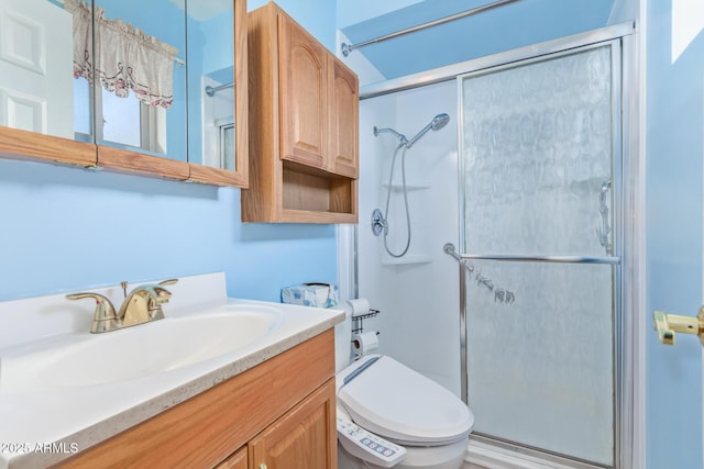 bathroom featuring vanity, toilet, and a shower with door