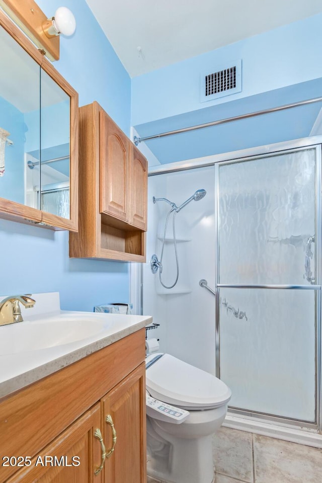 bathroom featuring tile patterned flooring, vanity, toilet, and a shower with door