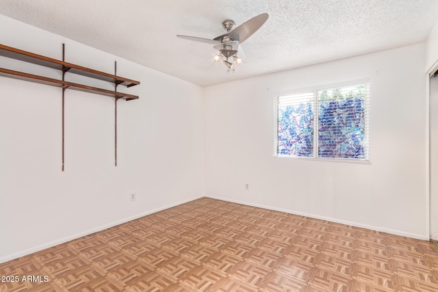 empty room with ceiling fan, a textured ceiling, and light parquet flooring