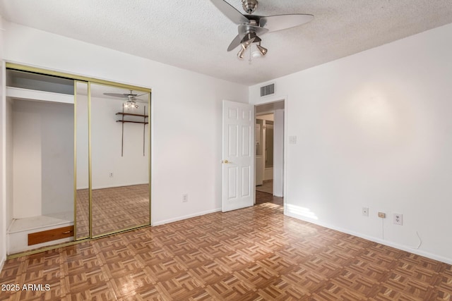 unfurnished bedroom featuring a textured ceiling, light parquet flooring, a closet, and ceiling fan