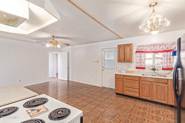 kitchen with pendant lighting, light parquet floors, sink, white range oven, and stainless steel refrigerator