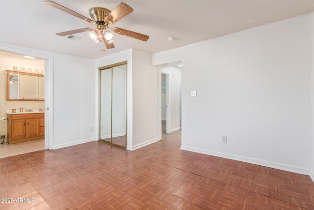 unfurnished bedroom with connected bathroom, ceiling fan, a closet, and parquet flooring